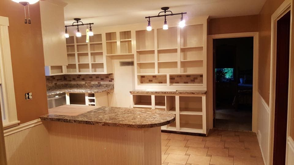 Kitchen with unfinished cabinets, granite countertops, and track lighting