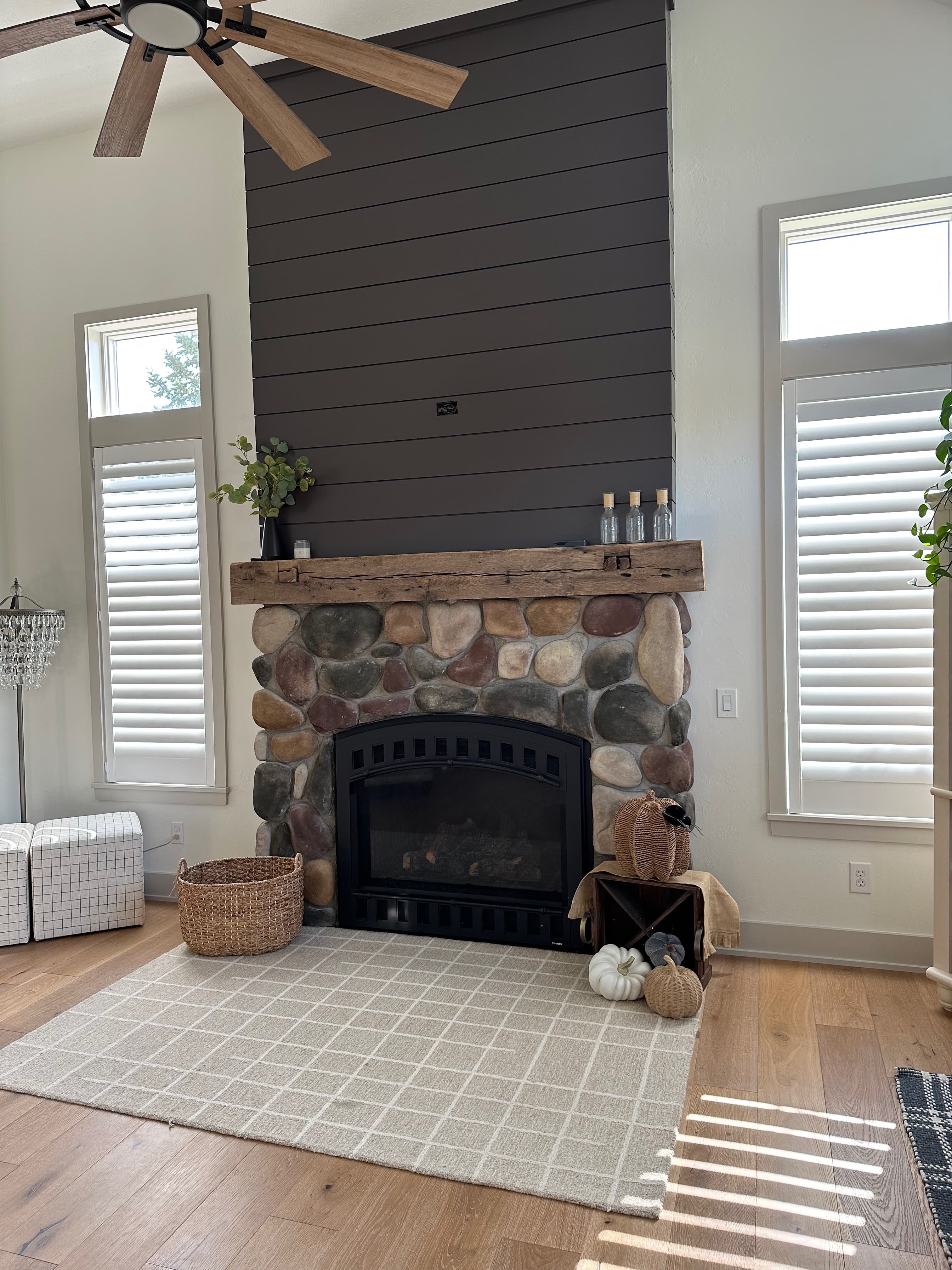 Stone fireplace with rustic wood mantel and dark gray shiplap accent wall
